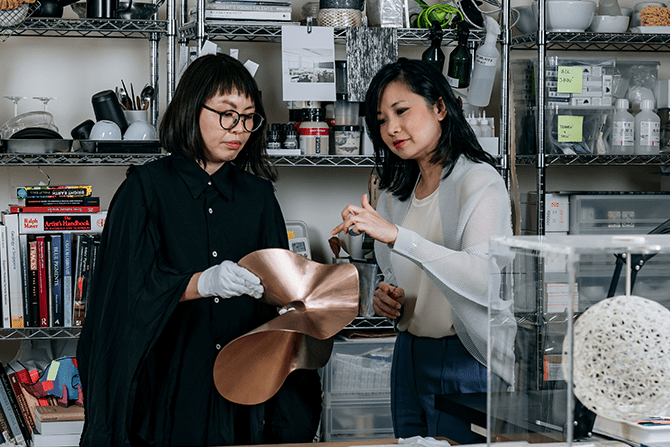 Grace Tan and gallerist Stephanie Fong studying a piece of artwork by Grace